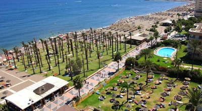 Strand med badegjester, palmer og promenade